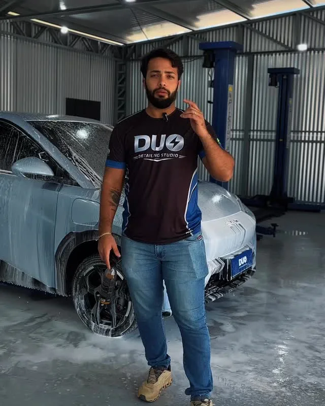 Profissional da DUO ao lado de um carro coberto de espuma durante lavagem detalhada com remoção de resíduos